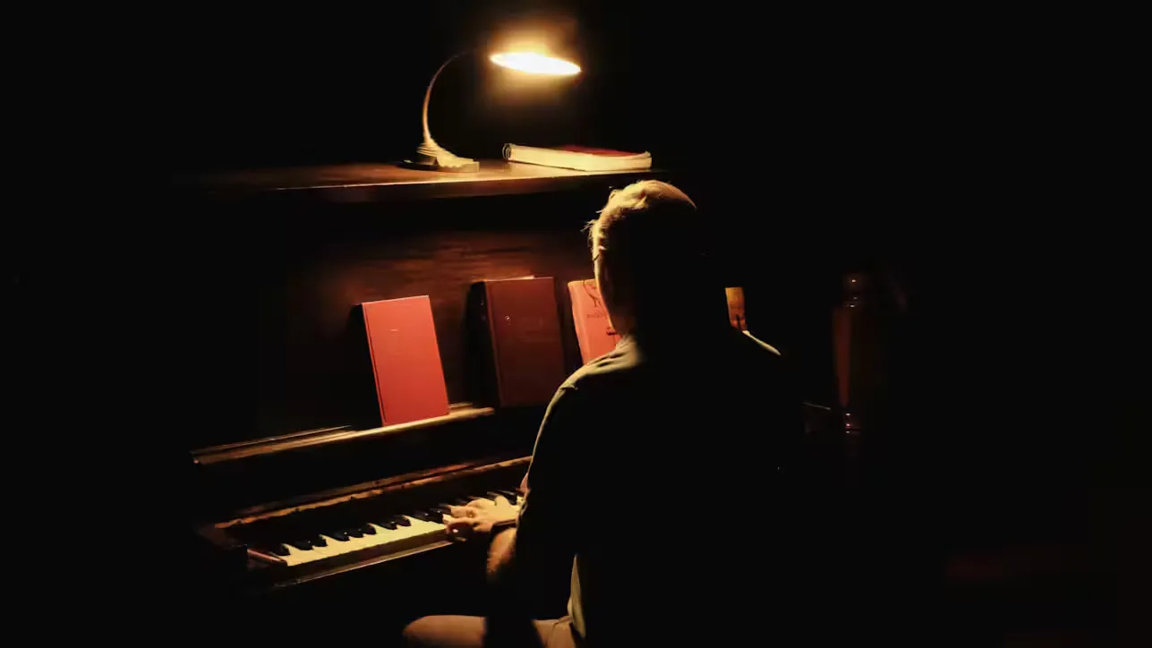 An adult piano learner practicing at an upright piano